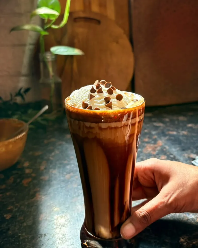 Chocolate drink held beside a kitchen counter